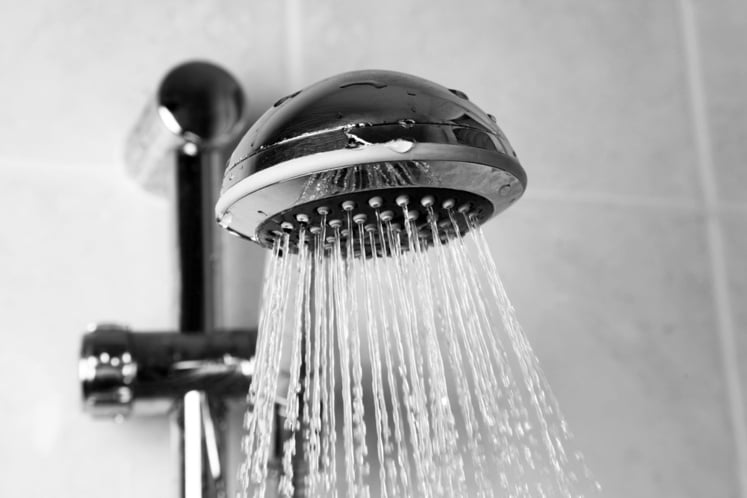 Shower attached to wall, with water coming out of the shower head.